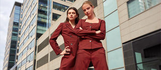 Two women in matching red outfits standing in front of a modern building.
